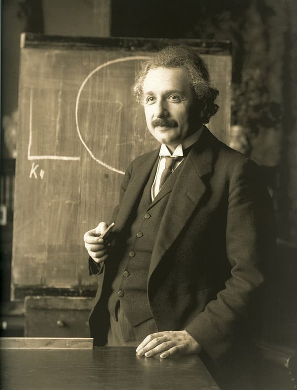 Albert Einstein em pé diante de um quadro-negro