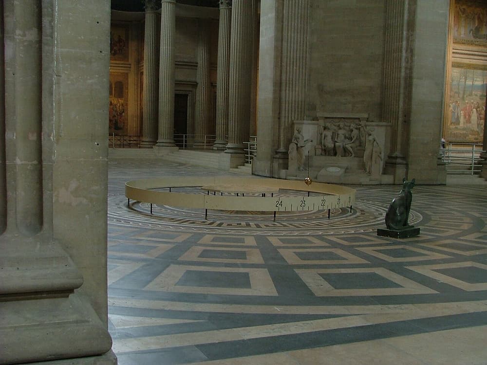 Pêndulo de Foucault no Panteão de Paris: um peso pendurado num fio longo sobre um círculo no chão