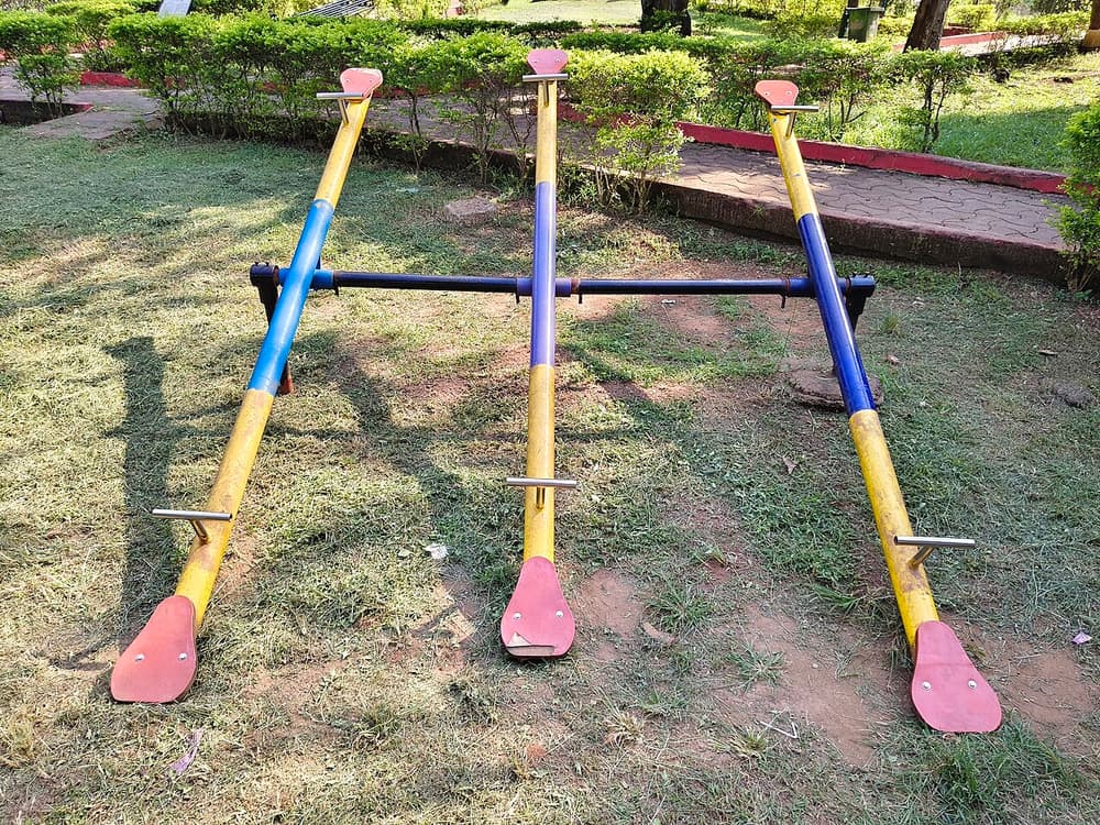 Três gangorras coloridas num gramado