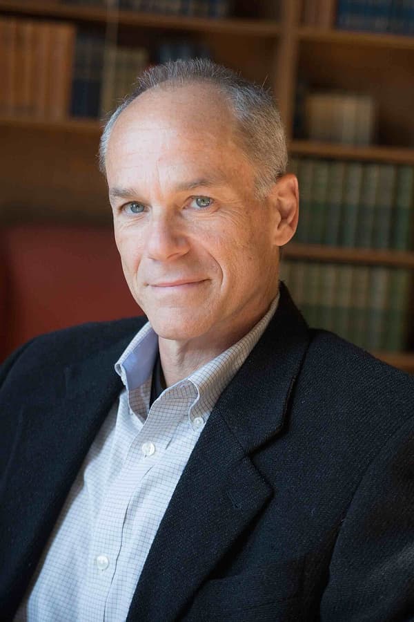 Marcelo Gleiser de terno, diante de uma estante de livros