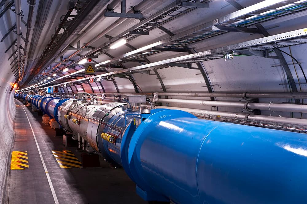Túnel comprido e curvo com um tubo azul enorme, o acelerador de partículas LHC