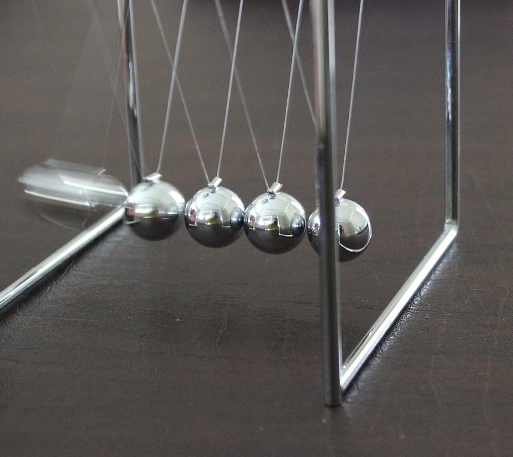 Pêndulo de Newton: cinco bolas de metal penduradas em fios, a primeira afastada das outras