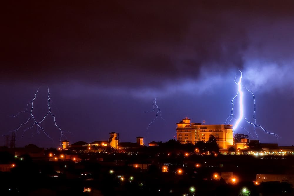 Vários raios caindo sobre uma cidade iluminada, à noite