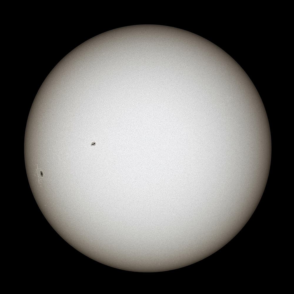O Sol fotografado com filtro especial: um disco claro com duas manchas escuras pequenas