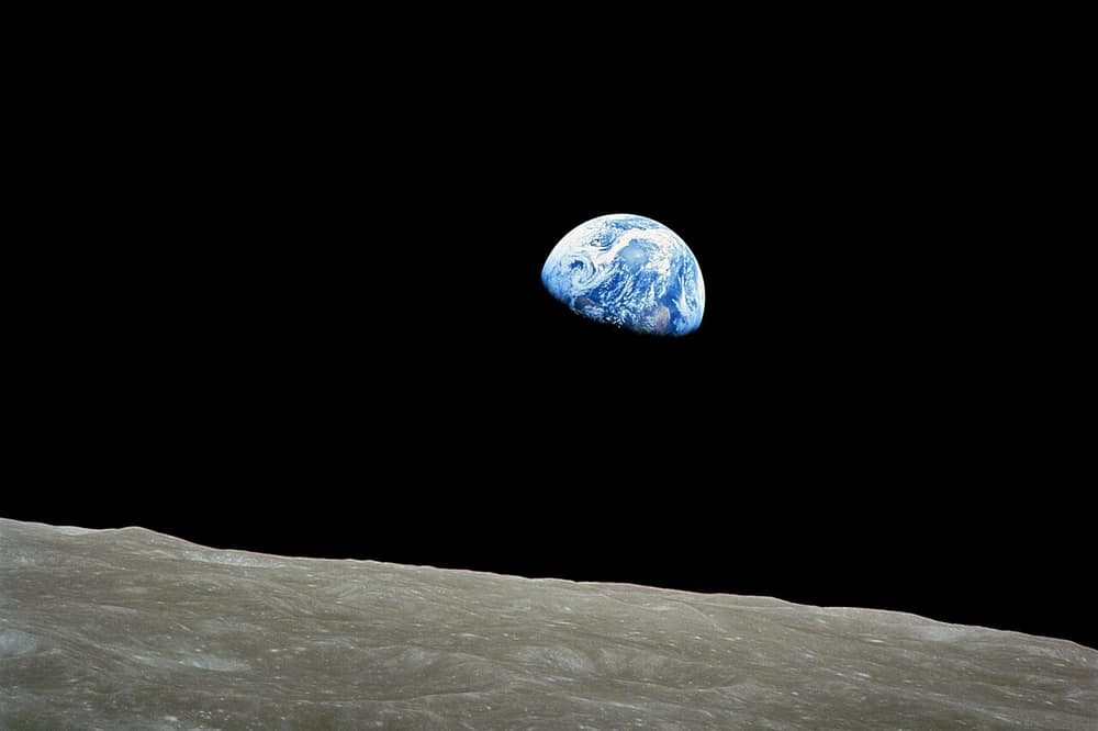 A Terra azul nascendo atrás do horizonte cinzento da Lua