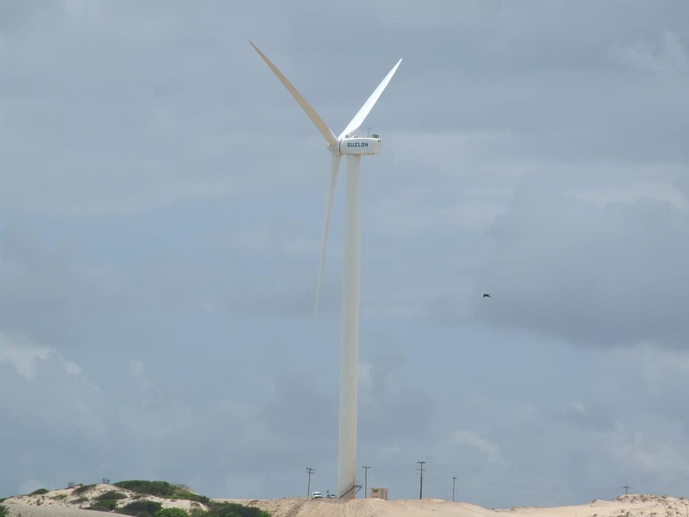 Um aerogerador branco, de três pás, contra o céu nublado
