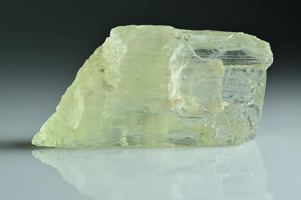 Cristal verde-claro e transparente de espodumênio sobre fundo cinza
