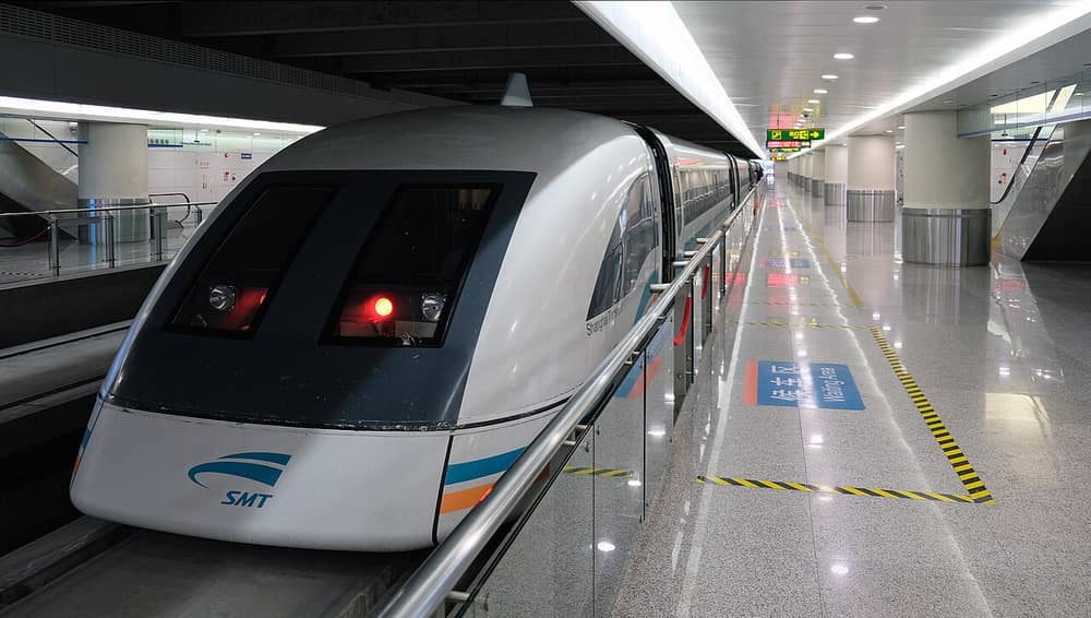 Trem branco de nariz arredondado parado numa estação moderna e iluminada