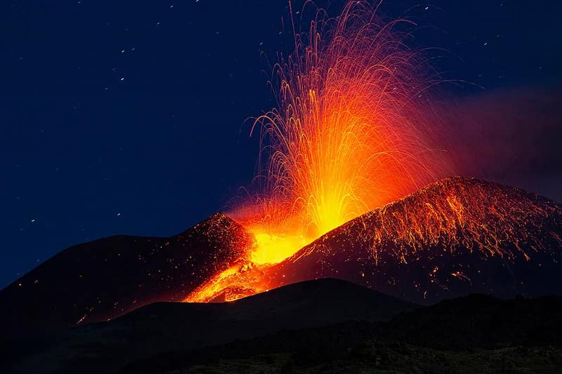 Vulcão Etna em erupção à noite, jogando lava e brasas para o alto