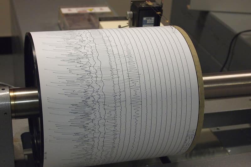 Sismógrafo com um papel enrolado num tambor, cheio de linhas tremidas