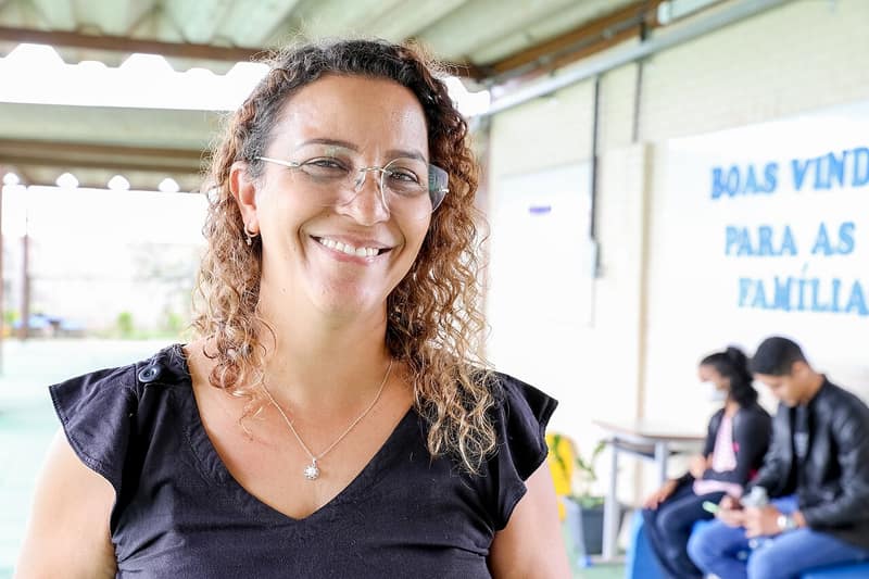 Professora sorrindo na entrada de uma escola bilíngue para surdos