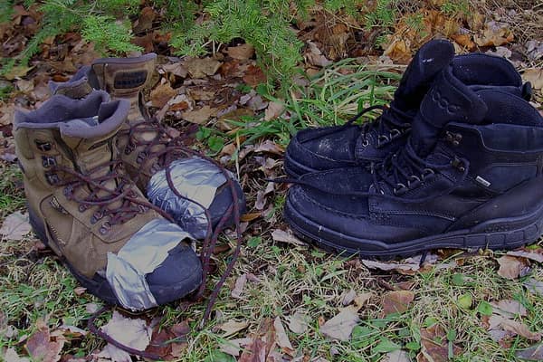 Dois pares de botas de caminhada usadas sobre a grama